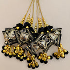 Black and gold cushion latkan tassel held in a hand to show its design and relative size
