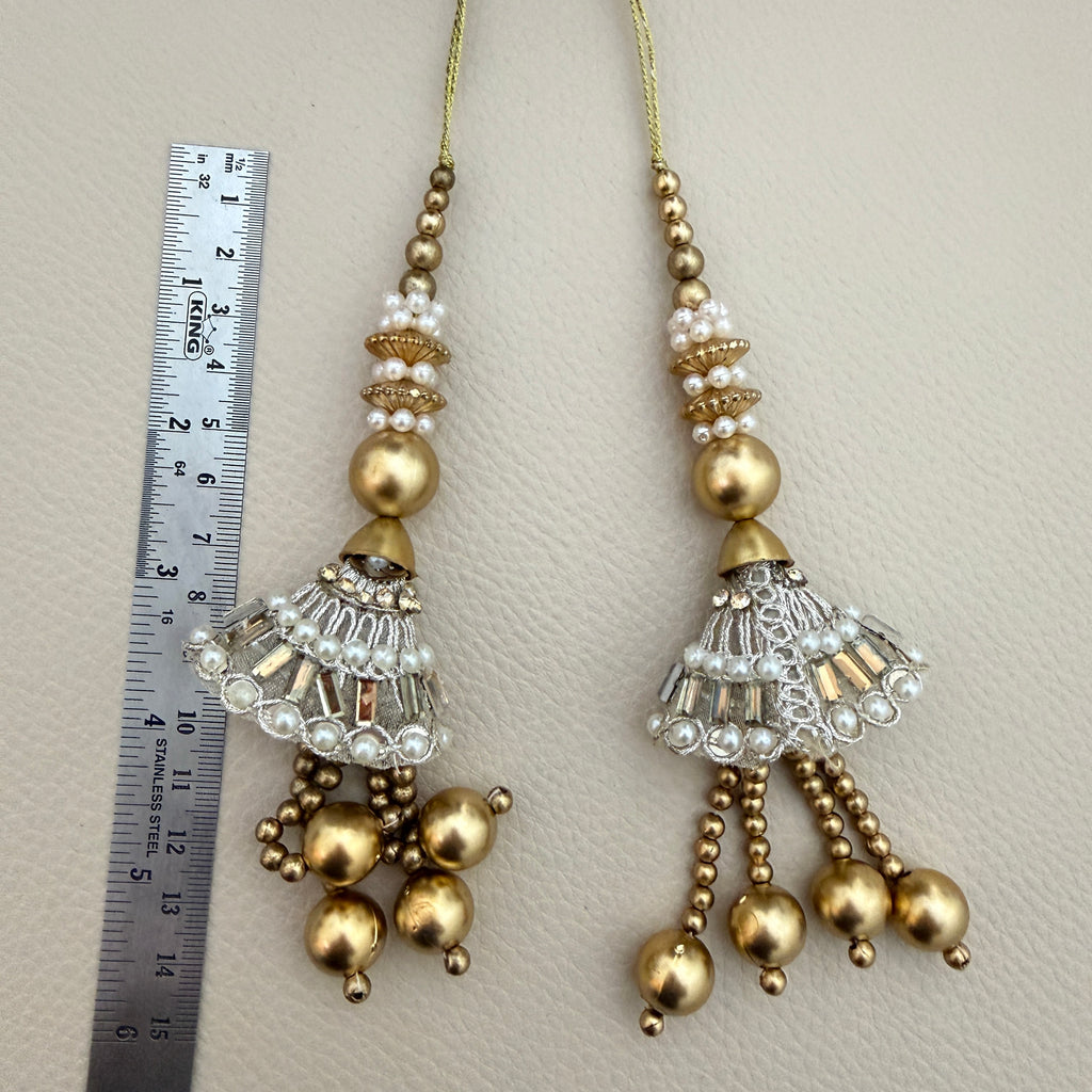 Gold and silver-tone beaded jhumka tassel held in a hand to show design and relative size