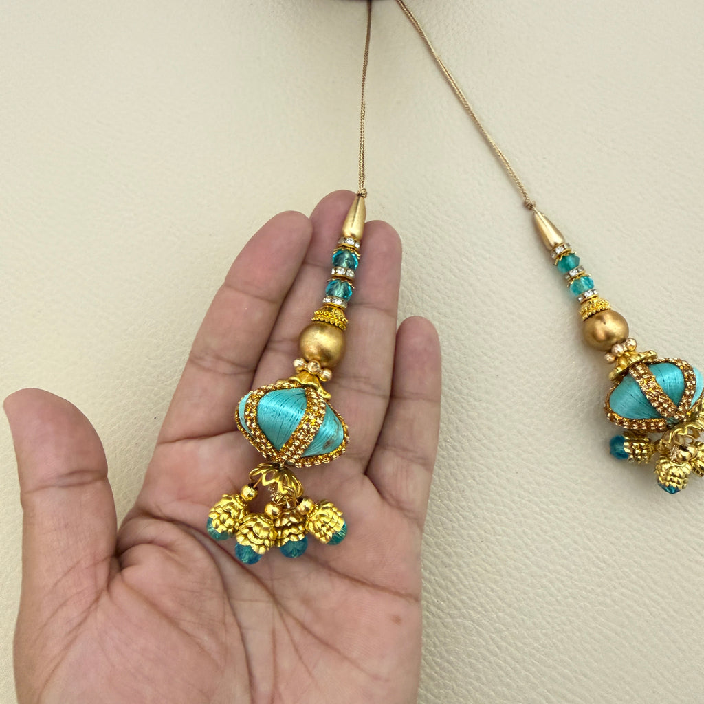 Turquoise and gold-tone tassels beside a ruler for size reference
