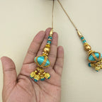Turquoise and gold-tone tassels beside a ruler for size reference