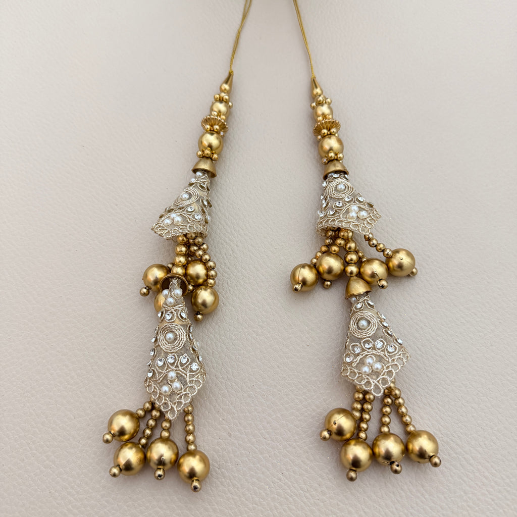 Gold-tone double-tier latkan tassel displayed on a hand for scale