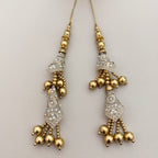 Gold-tone double-tier latkan tassel displayed on a hand for scale