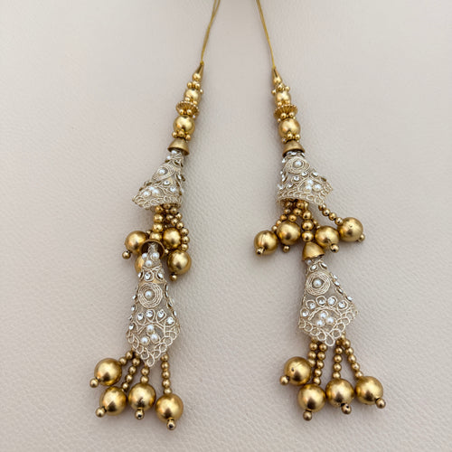 Gold-tone double-tier latkan tassel displayed on a hand for scale