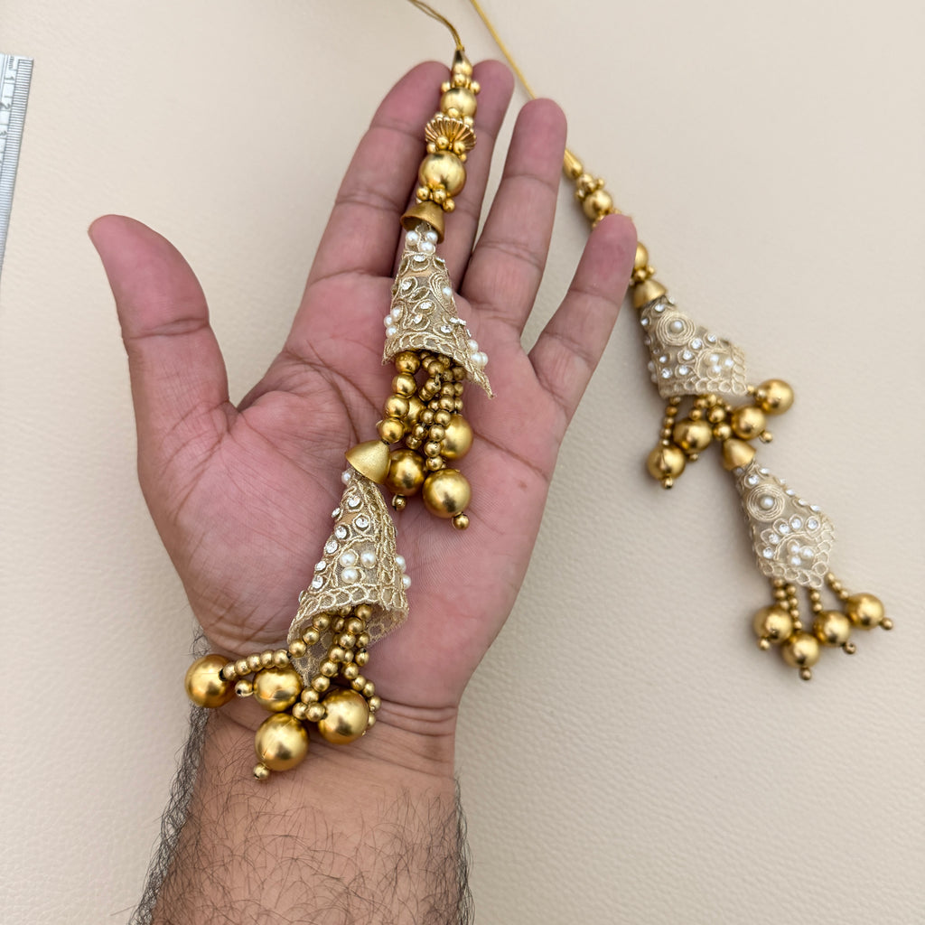 Pair of decorative cone latkan tassels beside a ruler for size reference