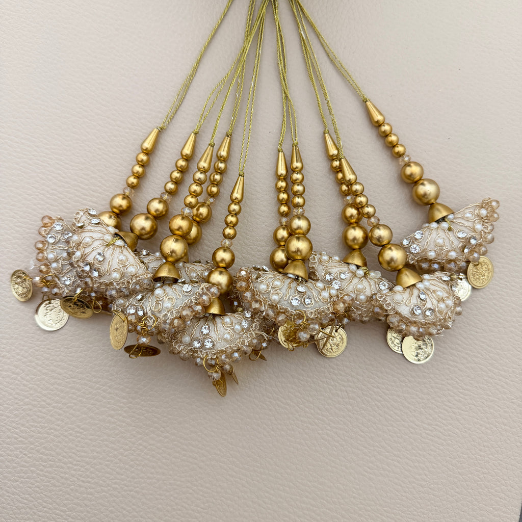 Ivory and gold latkan tassels beside a ruler for size reference