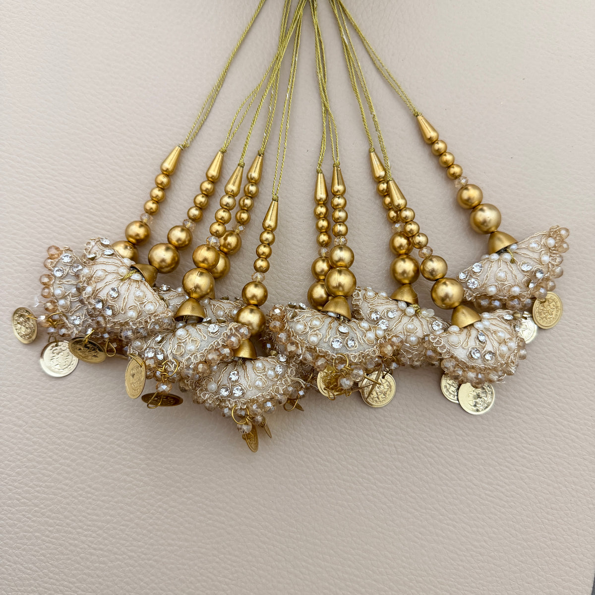 Ivory and gold latkan tassels beside a ruler for size reference