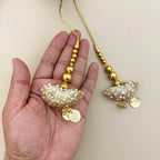 Ivory and gold umbrella latkan tassel held in a hand showing decorative beadwork and coin charms