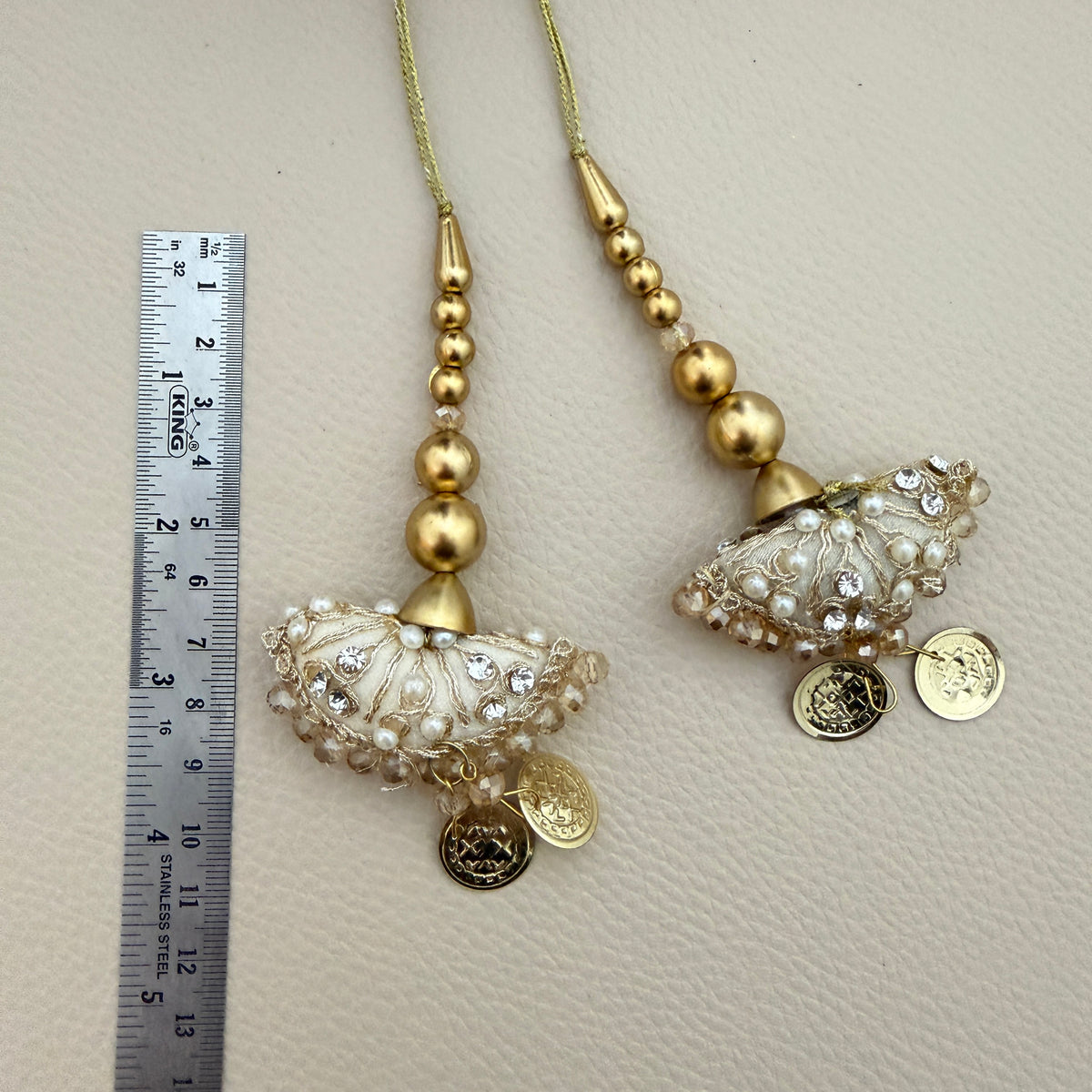 Group view of ivory and gold coin charm tassels; product sold as a pack of two