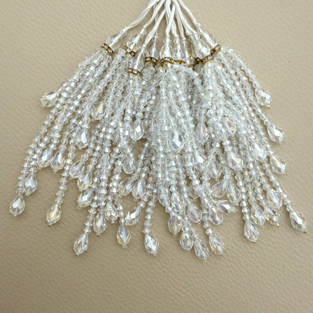 Clear faceted bead tassel held in a hand showing graduated strands and teardrop ends