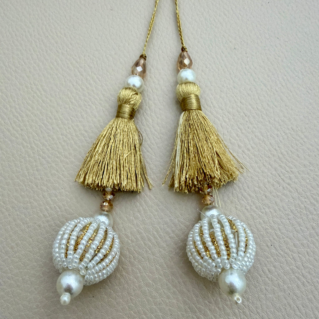 Group of gold thread tassels with pearl-look beaded balls; each pack contains two pieces