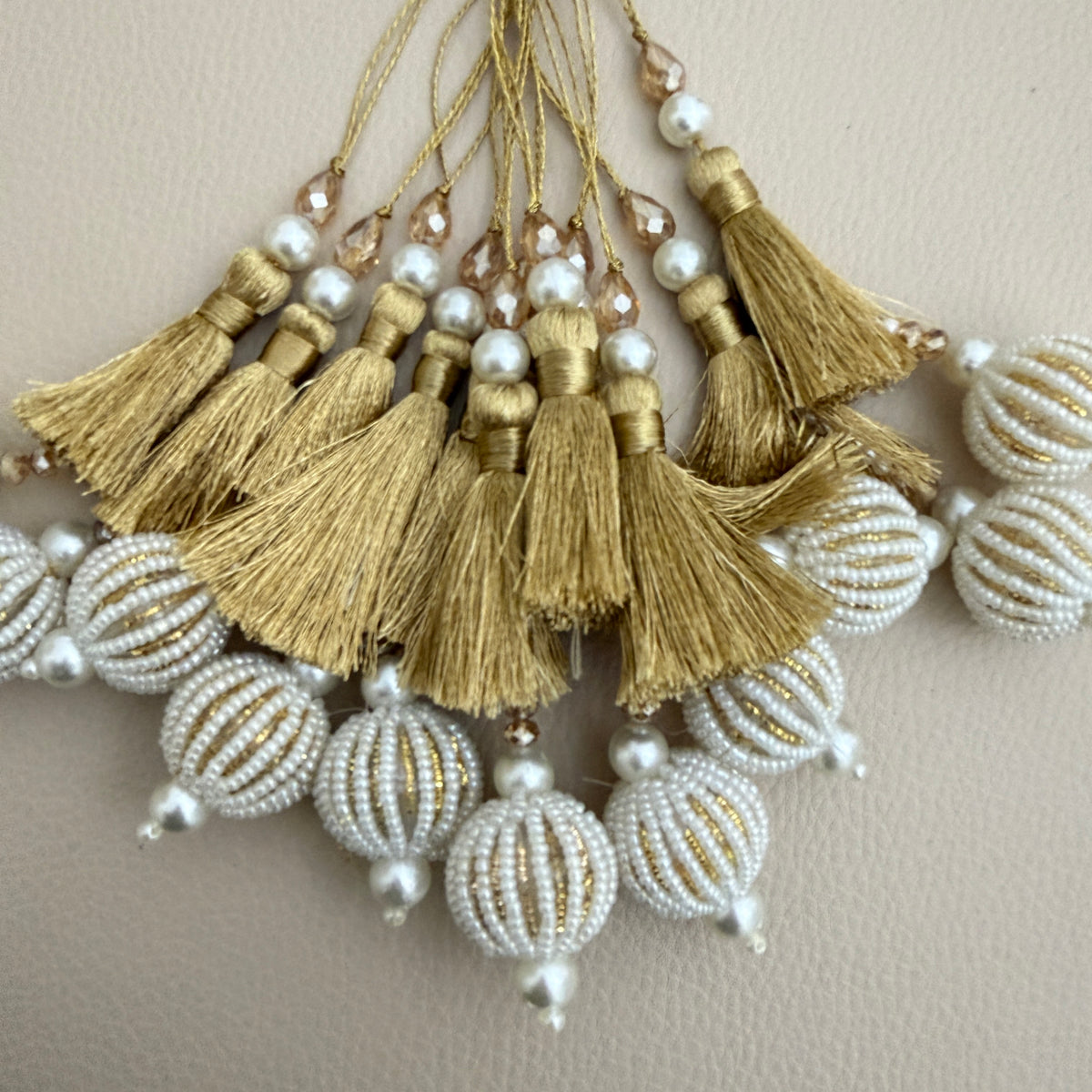 Gold thread and pearl-look beaded ball tassels beside a ruler for visual size reference