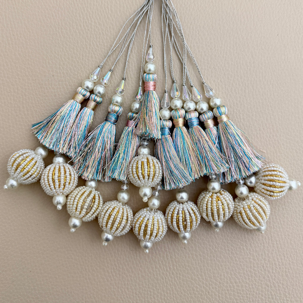 Pastel multicolour thread tassel held in a hand showing pearl-look beaded ball pendant