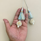Two pastel multicolour latkan tassels beside a ruler for visual size reference