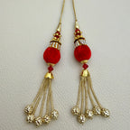 Close-up of red pom pom latkan tassel with gold-tone chains held in a hand