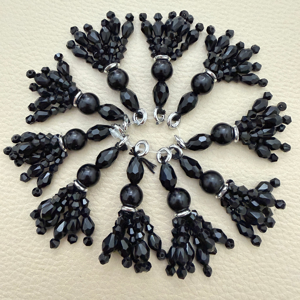 Black beaded latkan tassel with faceted bead drops and silver-tone accents held in a hand