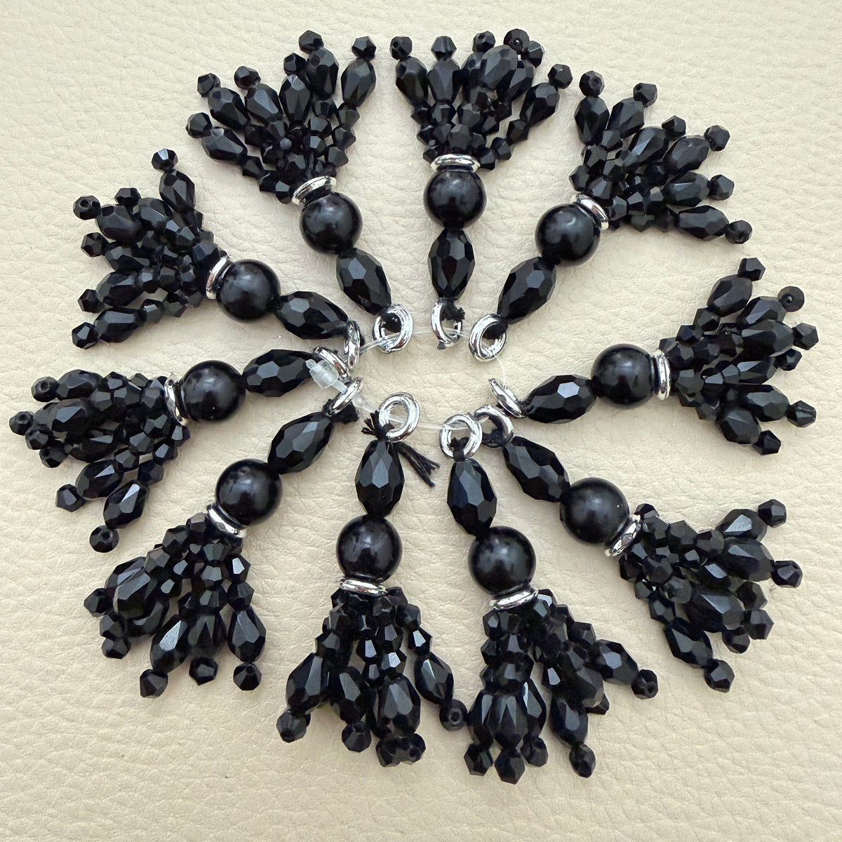 Black beaded latkan tassel with faceted bead drops and silver-tone accents held in a hand