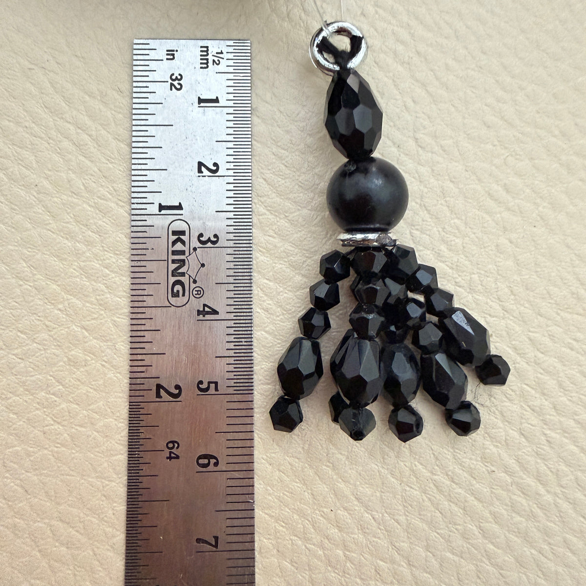 Black beaded latkan tassel beside a ruler for size reference