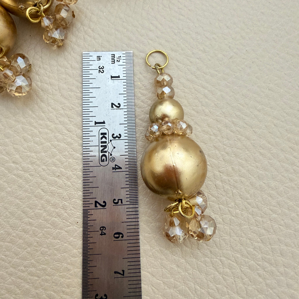 Detail of gold-tone round beads and dangling champagne-coloured beads on latkan tassel